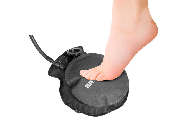 Fuß setzt auf ein rundes schwarzes Massagegerät mit Kabel