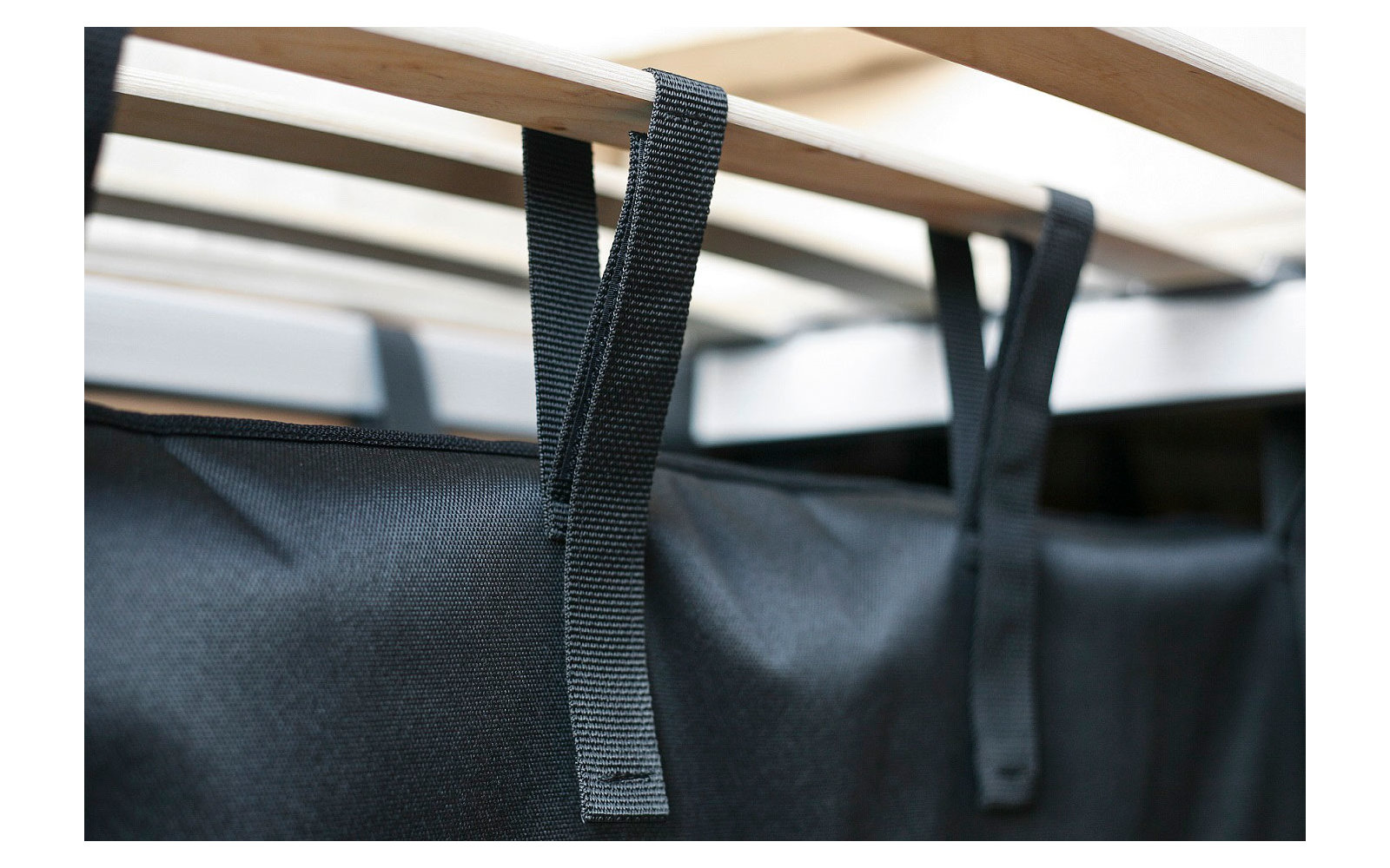 Schwarzer Stoff mit Laschen hängt an einer Holzleiste