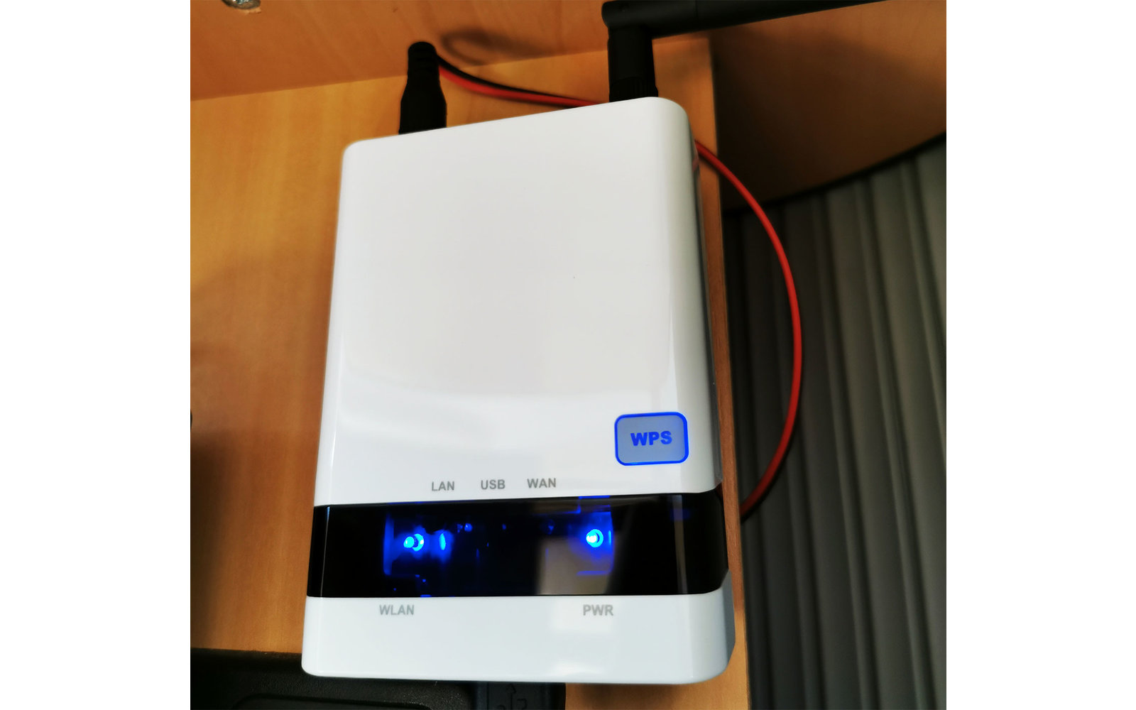 Weißes elektronisches Gerät mit Display und blauen Lichtern, an einer Wand montiert