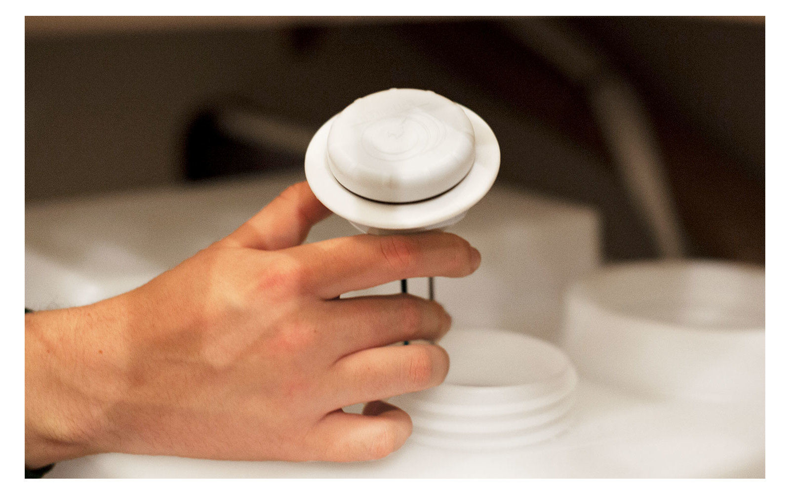 Hand hält eine Tasse mit weißem Getränk, auf einem Holztisch