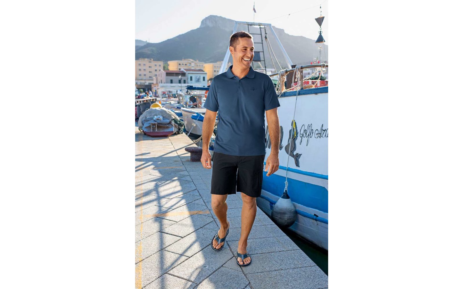 Mann in blauer Kleidung steht auf einem Steg neben Händen und Booten