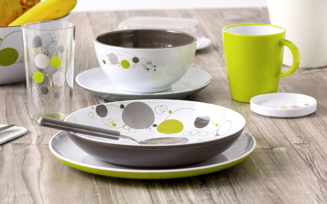 Teller, Schale, Tasse und Glas mit grün-grauen Punkten auf einem Holztisch