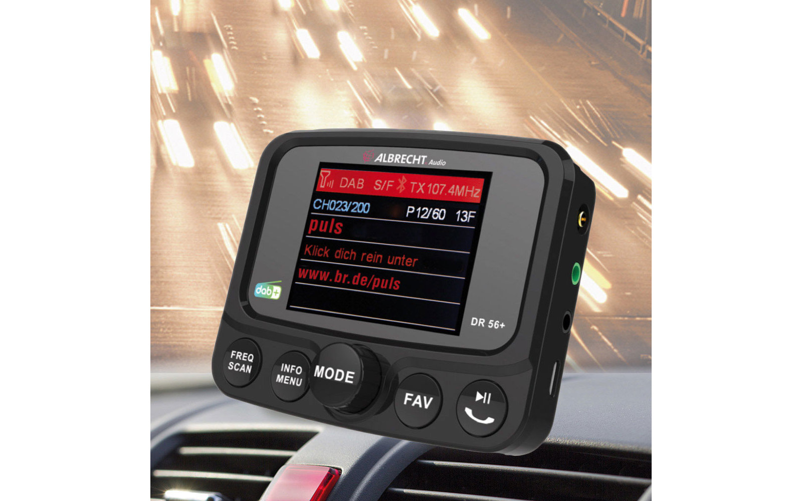 Ein digitales Gerät mit beleuchtetem Display auf einem Armaturenbrett, im Hintergrund verschwommene Straßenlichter