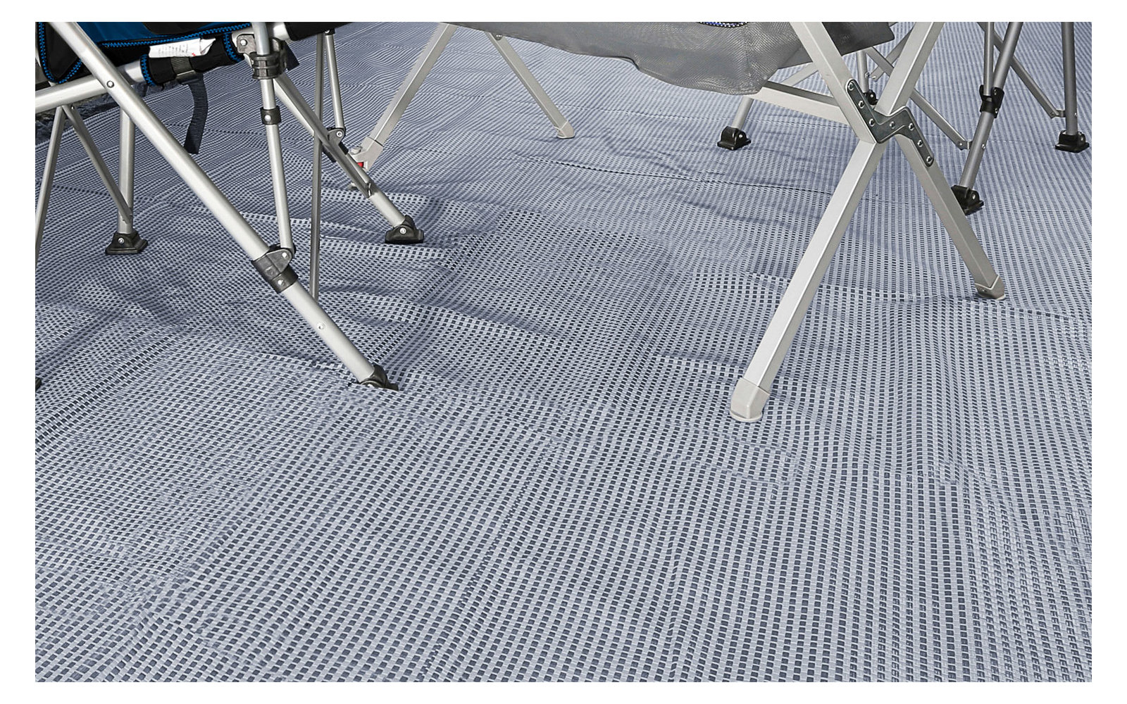 Gambe di sedie da campeggio su un tappeto grigio a strisce per esterni