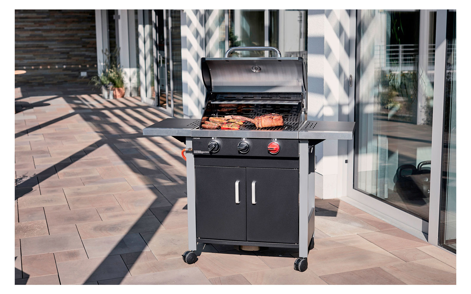 Gasgrill auf Terrasse mit Steaks und Würstchen, Sonnenschein und Schatten