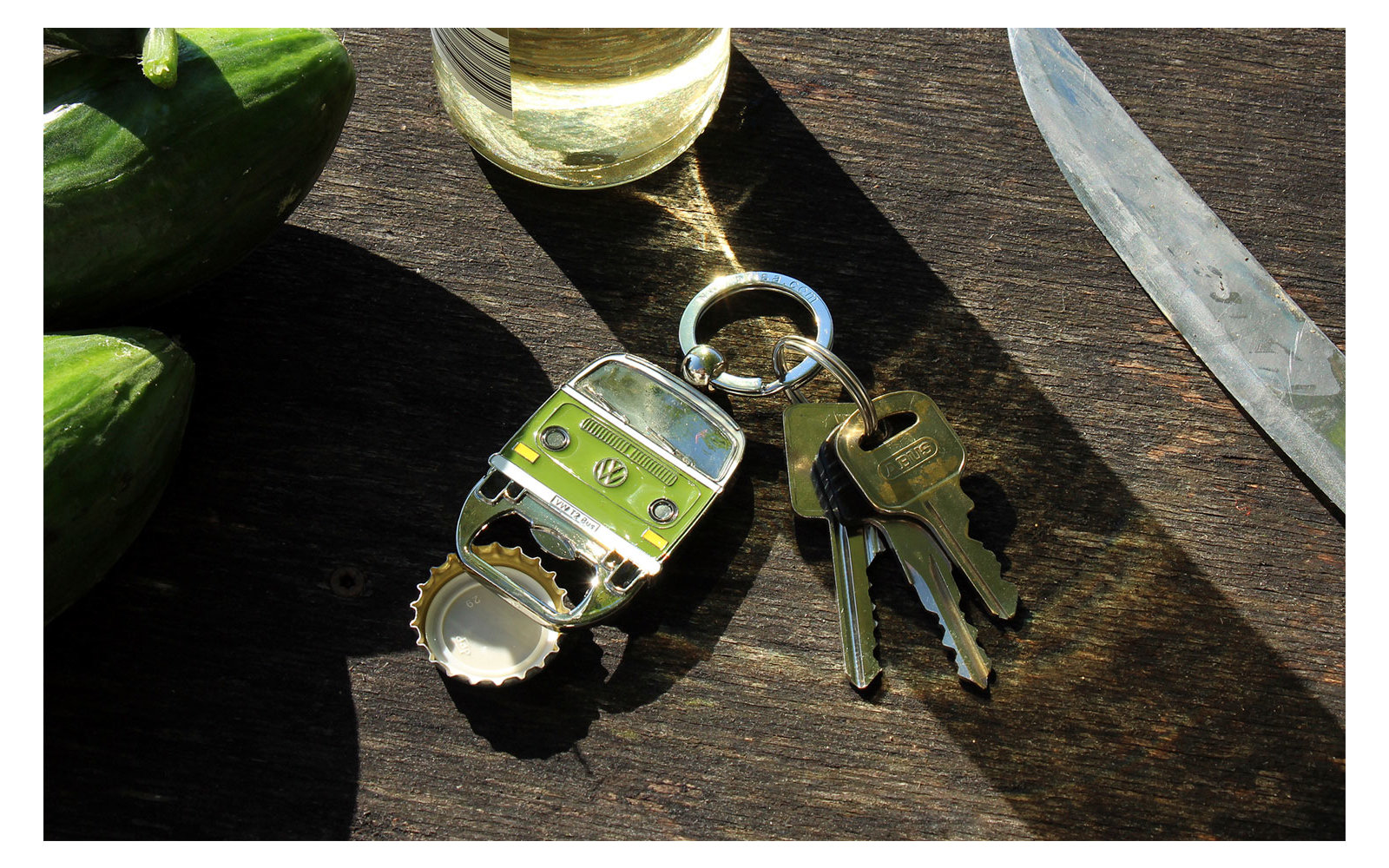 Sleutelhanger met twee sleutels, flesopener en mes op een donkere houten tafel