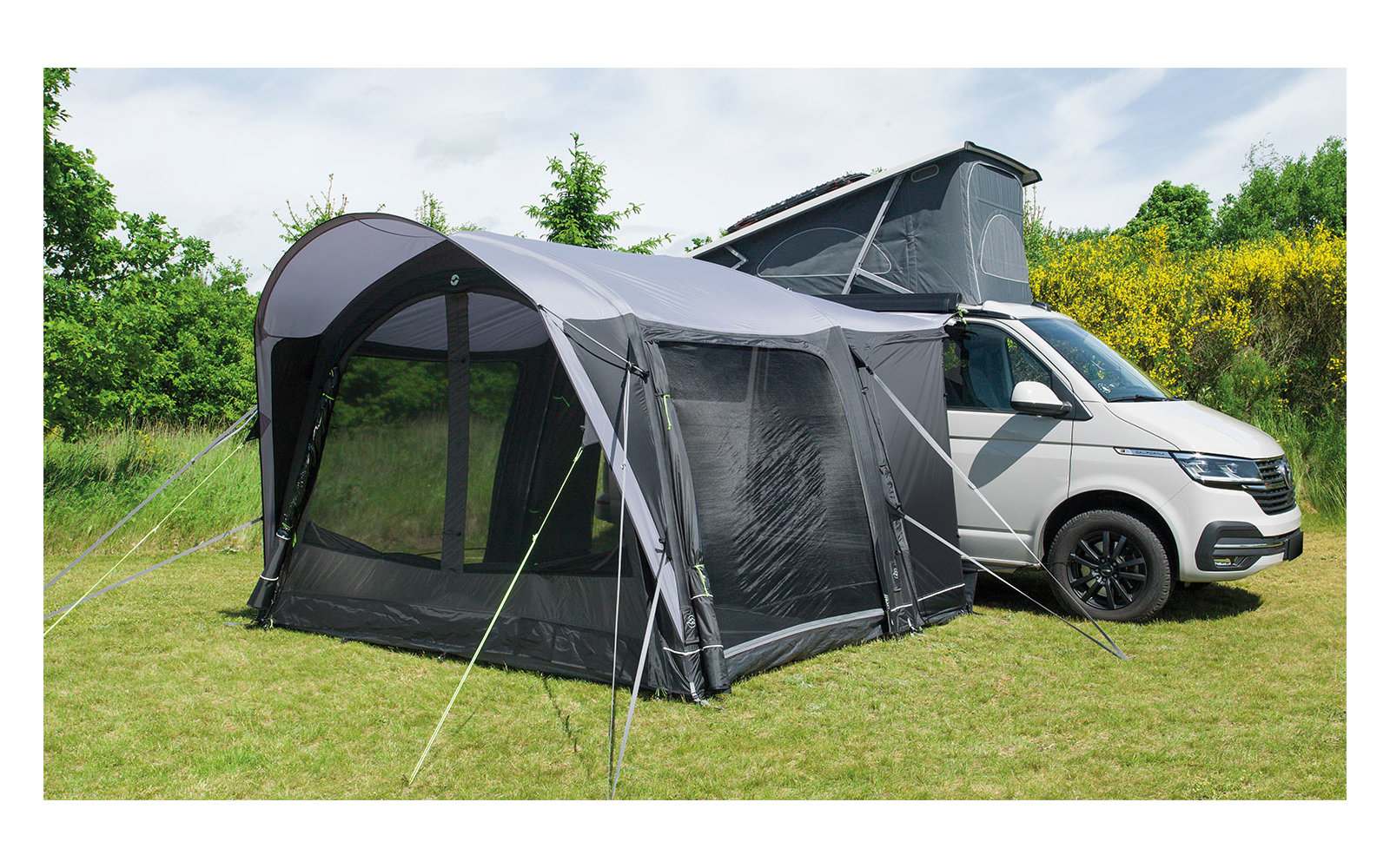 Wohnmobil mit angebautem Vorzelt auf einer grünen Wiese