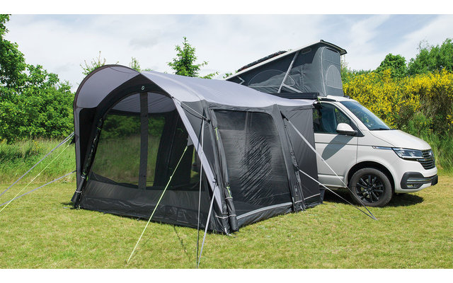 Wohnmobil mit angebautem Vorzelt auf einer grünen Wiese