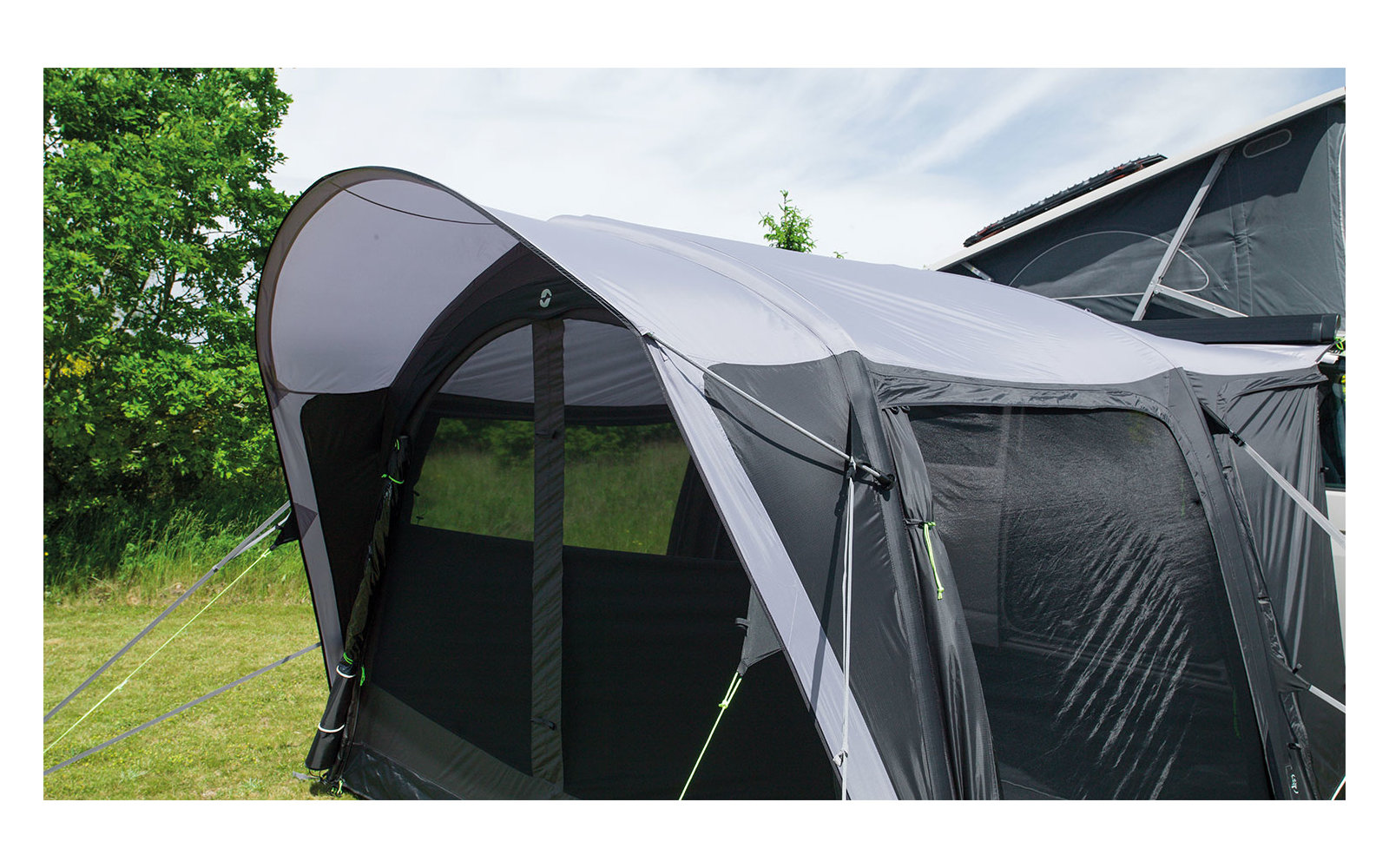 Graues Zelt mit schwarzen Fenstern auf einer grünen Wiese