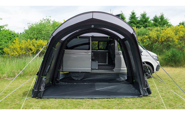 Schwarzes freistehendes Zelt auf einer Wiese, dahinter ein weißes Auto und grüne Bäume