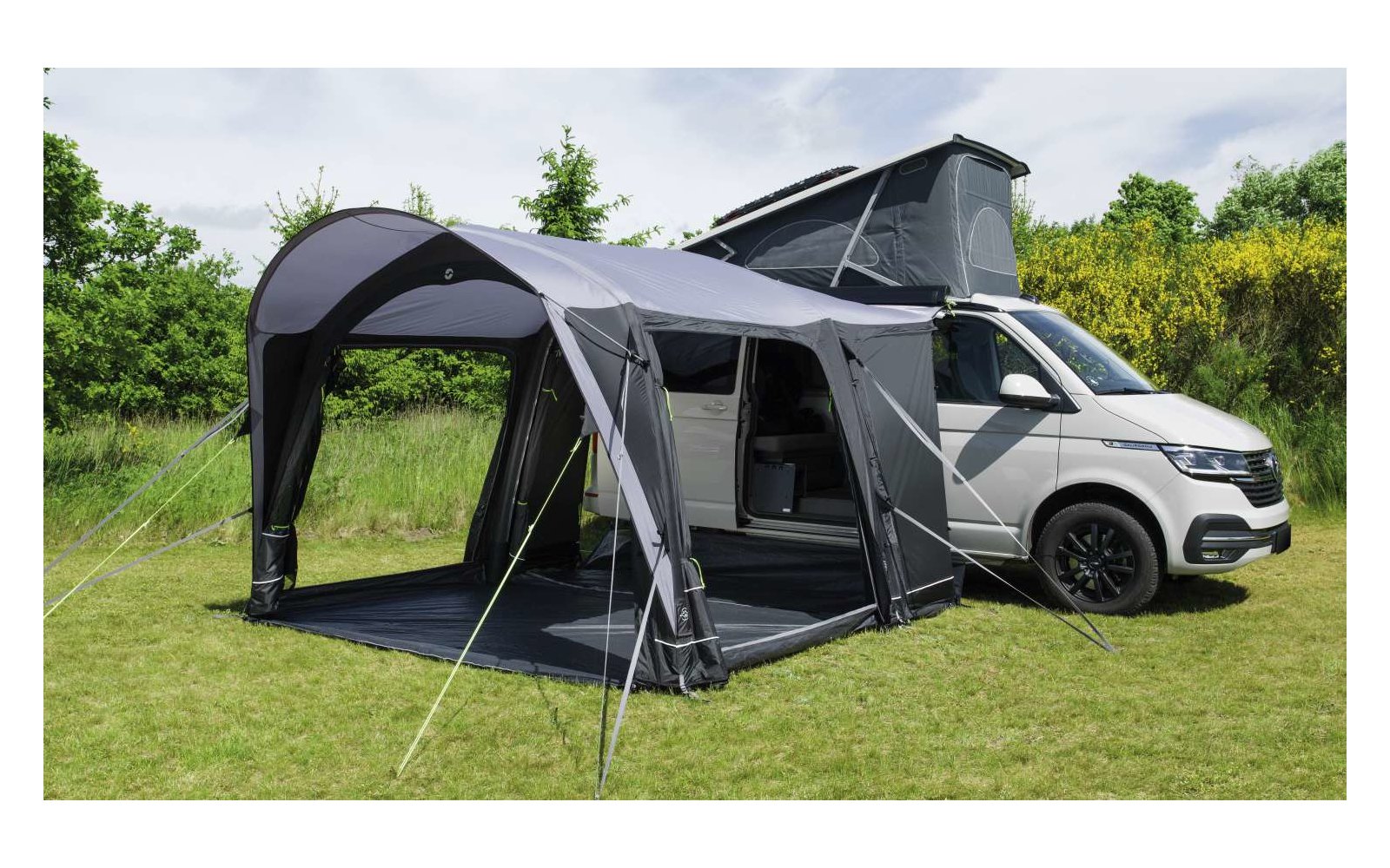 Wohnmobil mit angebautem großen grauen Vorzelt auf grüner Wiese