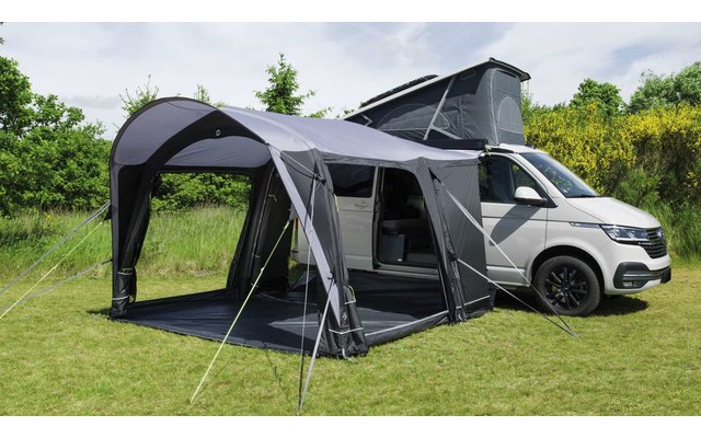 Wohnmobil mit angebautem großen grauen Vorzelt auf grüner Wiese