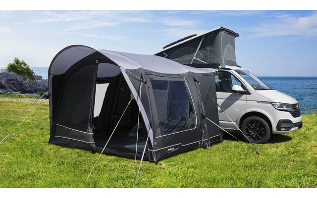 Auto mit aufgespanntem Zelt auf Wiese bei klarem Himmel