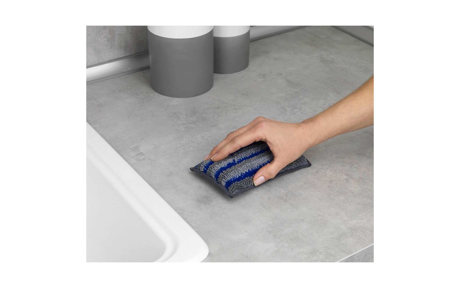 Hand reinigt graue Oberfläche mit blauem Schwamm