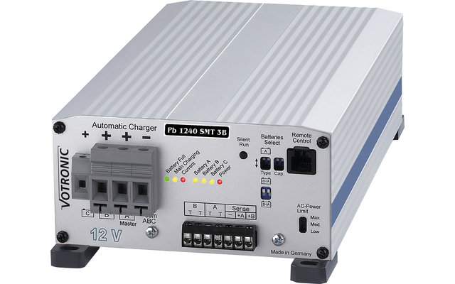 Zilverkleurig elektronisch apparaat met meerdere aansluitingen en indicatorlampjes, links drie rode en groene plus- en min-symbolen, ventilatiesleuven bovenop