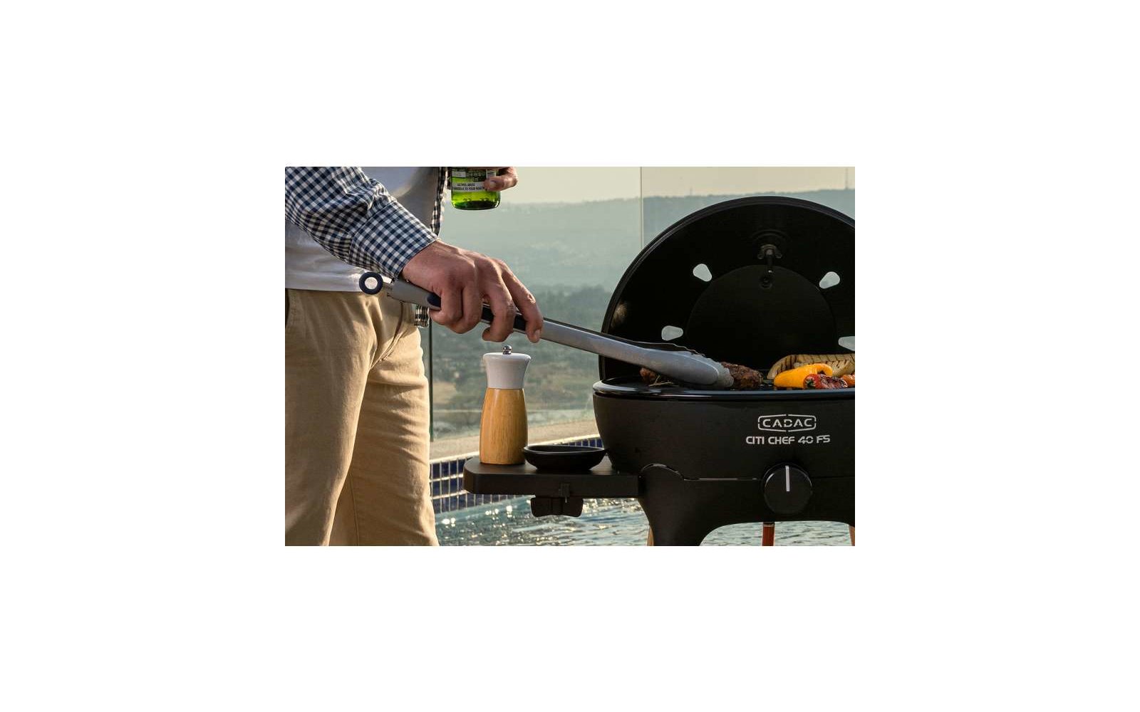 Uomo che griglia con una pinza davanti a un barbecue a carbone