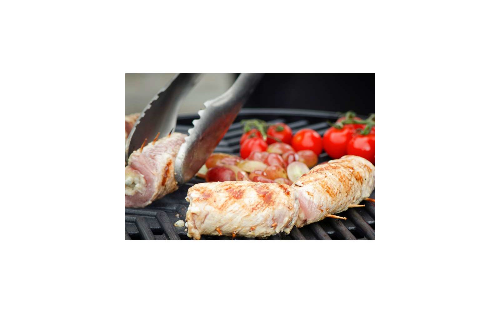 Filetto di pollo alla griglia su una griglia con pomodori sullo sfondo
