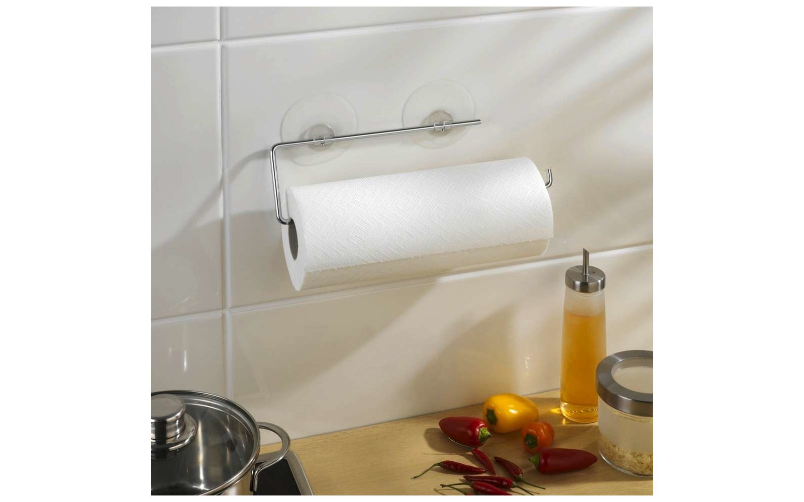 Küchenrolle auf einer Halterung an weißer Wand, daneben Flasche mit Öl und Gewürze auf der Arbeitsfläche