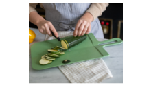 Person schneidet eine Gurke in Scheiben auf einem grünen Schneidebrett