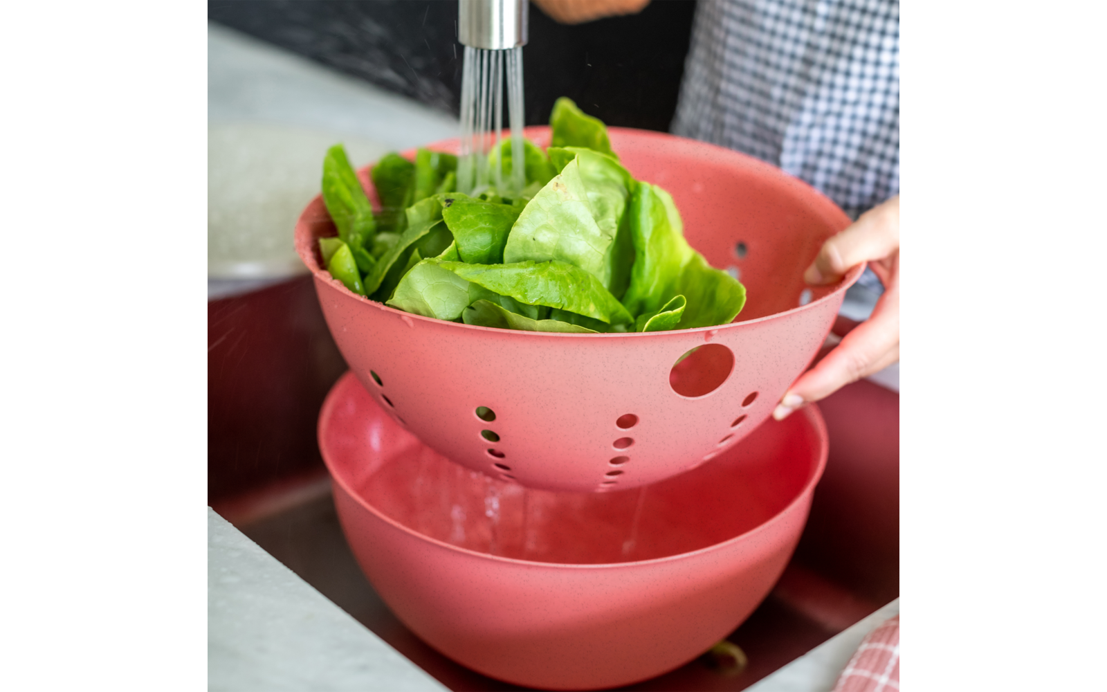 Frischer grüner Salat in einem roten Sieb über einer roten Schüssel