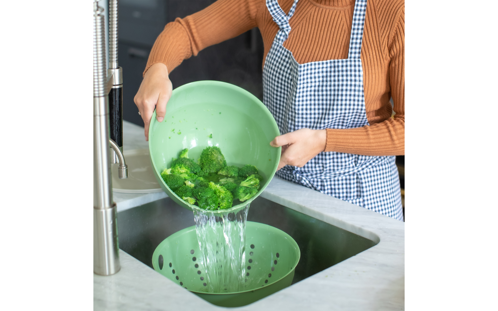 Person wäscht grüne Paprika in einer Spüle