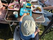 Personen sitzen an einem Tisch im Freien und essen gemeinsam