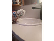 Mano sosteniendo botella sobre el lavabo