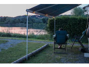 Tent with open entrance and camping chair on grassy ground with lake in the background