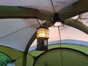 Windlicht hängt unter einem Sonnensegel bei Sonnenuntergang