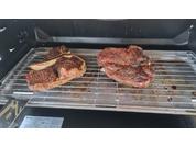 Deux steaks crus posés sur une grille à l'intérieur d'un gril