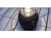 Black lantern with light turned on on a white wooden table