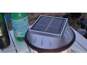 Solar-powered lamp on a white wooden chair with a green bottle in the background