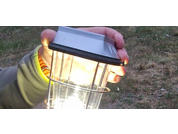 Hand holding a solar light lamp above grass