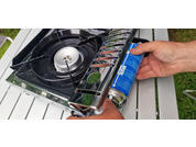 Hand attaching a gas cartridge to a portable camping stove