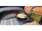 Pancakes are being cooked on a portable camping stove outdoors