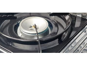 A gas stove with a burning gas flame under a white pot lid