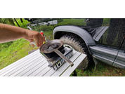 Hand holding a removed spare tire next to a black car