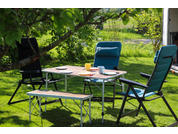 Tuin met een tafel en vier stoelen, glazen en een kan op de tafel