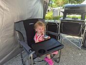 Little girl sitting in a high chair outdoors