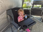 Small child sitting in a high chair holding a pink toy