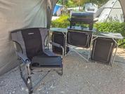 Two black camping chairs in front of a tent outdoors