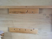 Sperrholzplatte mit zwei quer befestigten Holzlatten, sichtbaren Schrauben und einem runden Ausschnitt unten links