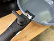 Black handle attached to the side of a gray metal pan, pan on a wooden board