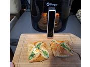Due fagottini dorati con ripieno verde visibile su un tagliere di legno; sullo sfondo una friggitrice ad aria nera con il logo 'Berger'