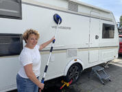 Femme debout devant un camping-car blanc pointant vers le logo sur le côté