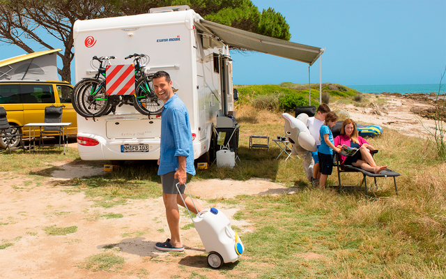 Woman with dog in front of a camper van on a sunny day