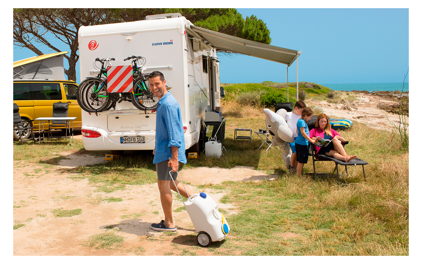Woman with dog in front of a camper van on a sunny day