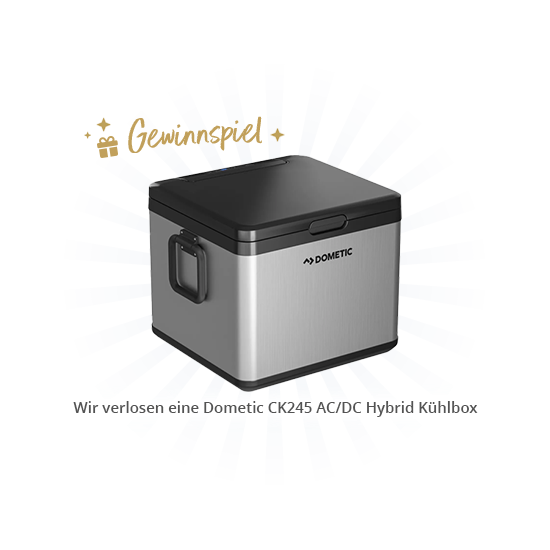 Silberne, rechteckige Dometic CK245 Kühlbox mit schwarzem Deckel und Griffen vor blauem Strahlenhintergrund; goldene 'Gewinnspiel'-Grafik oben und weißes Textfeld mit dem Text 'Wir verlosen eine Dometic CK245 AC/DC Hybrid Kühlbox'