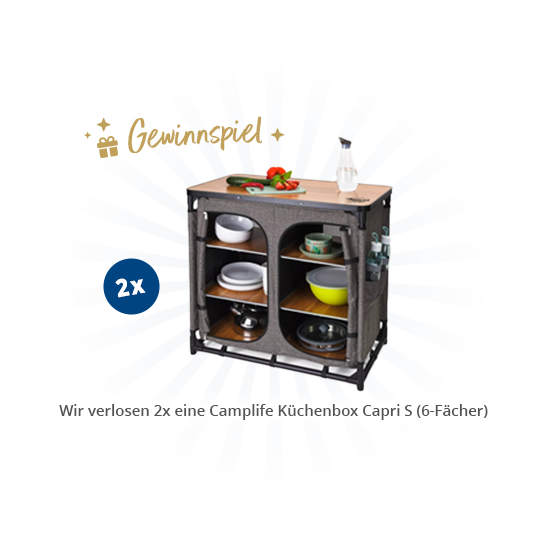 Offene 6‑Fächer-Küchenbox aus Holz und Metall mit Tellern, Schüsseln und Tassen; auf der Holzoberfläche Schneidebrett mit Tomaten und Salzstreuer; blauer Strahlenhintergrund, goldener Schriftzug 'Gewinnspiel', weiße Leiste mit dem Text 'Wir verlosen