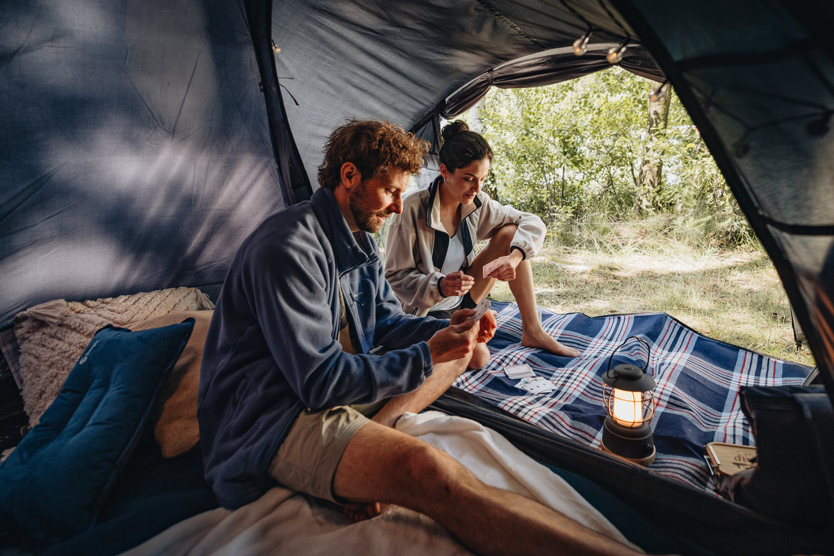 Ein P&auml;rchen spielt Karten beim Campen im Zelt.